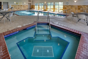 Uma piscina interior com várias pistas, guardaíles de segurança e área de estar com cadeiras.