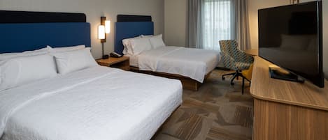 A hotel room with two beds, a television, a desk, and a chair.