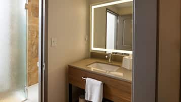 Un baño con lavamanos, espejo, toalla y papel higiénico.