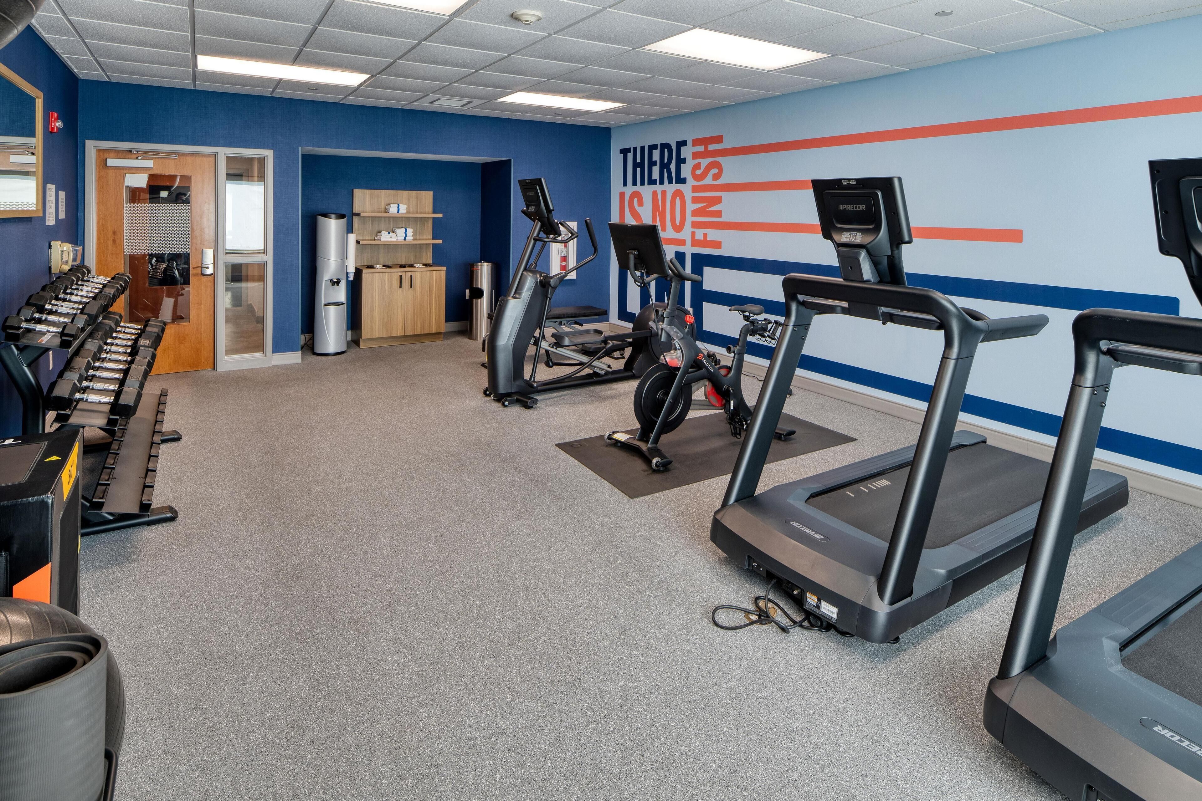 A gym with treadmills, elliptical machines, and free weights.