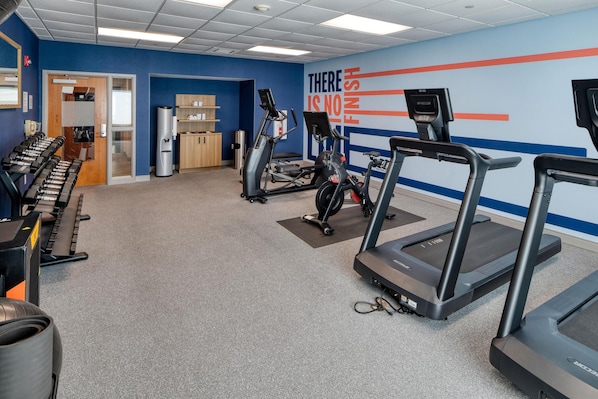 A gym with treadmills, elliptical machines, and free weights.