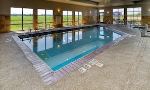 An indoor swimming pool with clear pool rules and no diving signs, surrounded by stone walls and large windows. - Hampton Inn Tomah (Tomah)