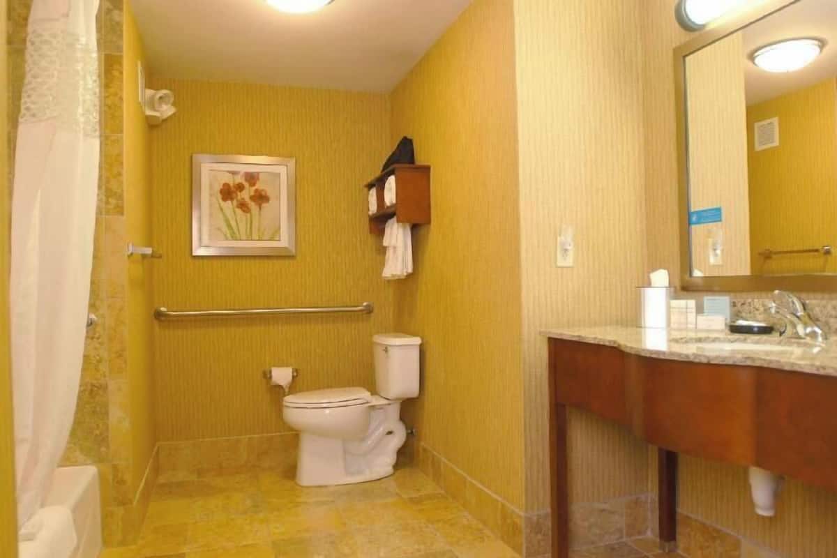 A bathroom with a toilet, shower, and vanity with a mirror.