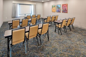 A conference room with tables and chairs, a projector screen, and a window with curtains.