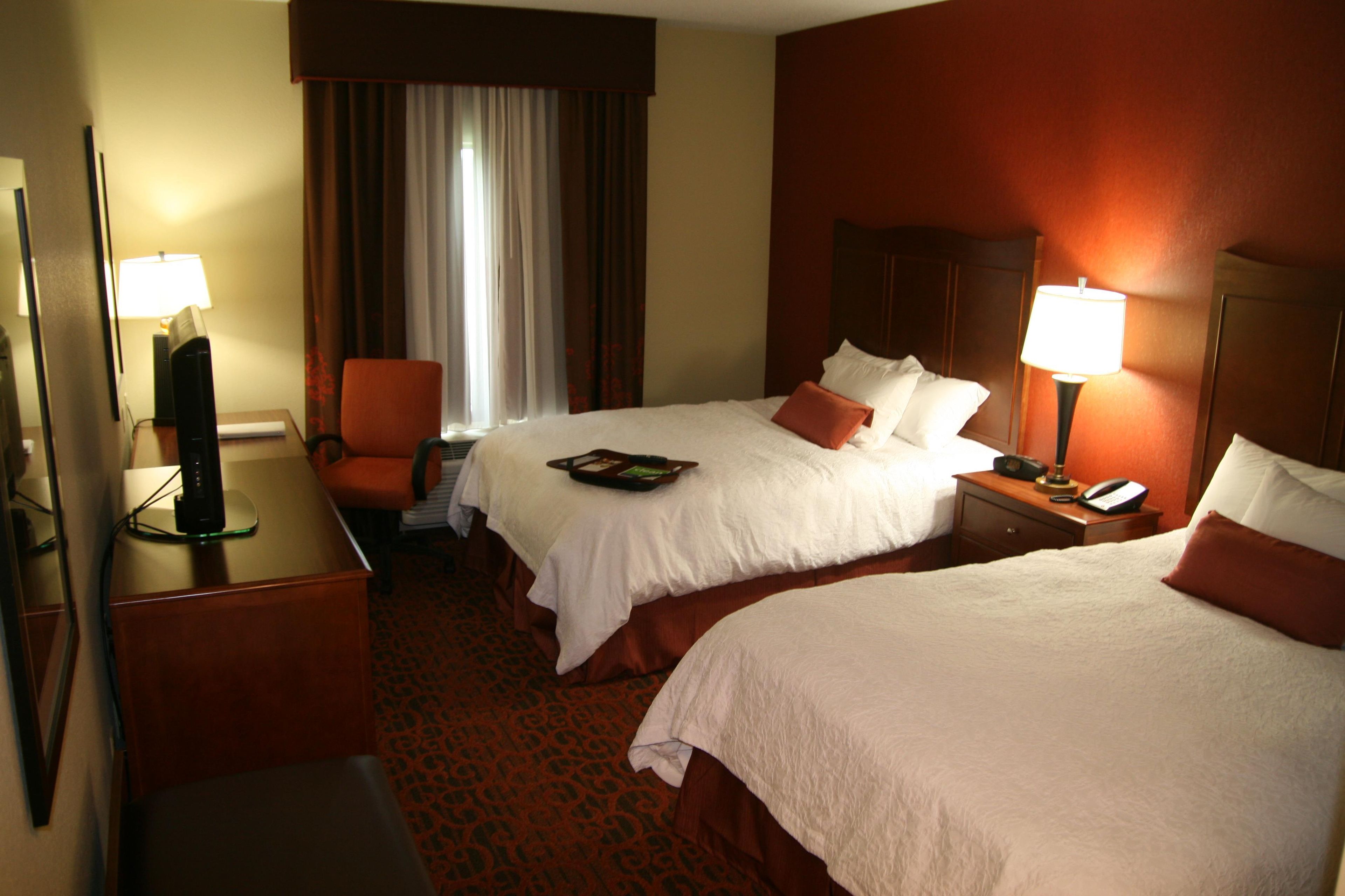 Une chambre d’hôtel avec deux lits, un bureau, une chaise et un téléviseur.