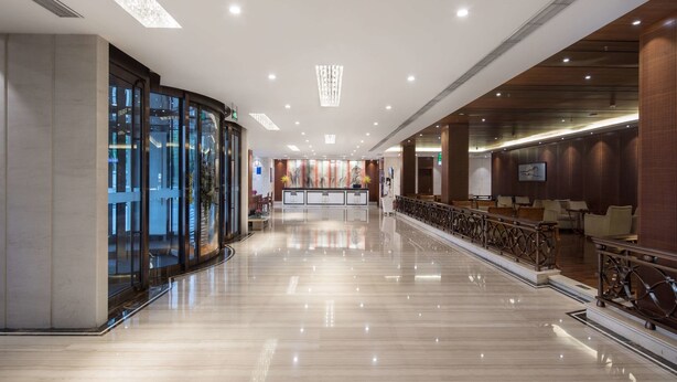 Um hall amplo com piso de mármore polido, balcão de recepção e área de estar com corrimão.