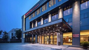 Uma entrada de hotel moderna com uma placa chamativa que diz "RAMADA BY WYNDHAM".