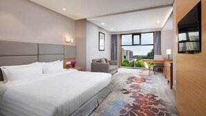 Quarto de hotel com uma cama grande, um sofá, uma escrivaninha e uma televisão.