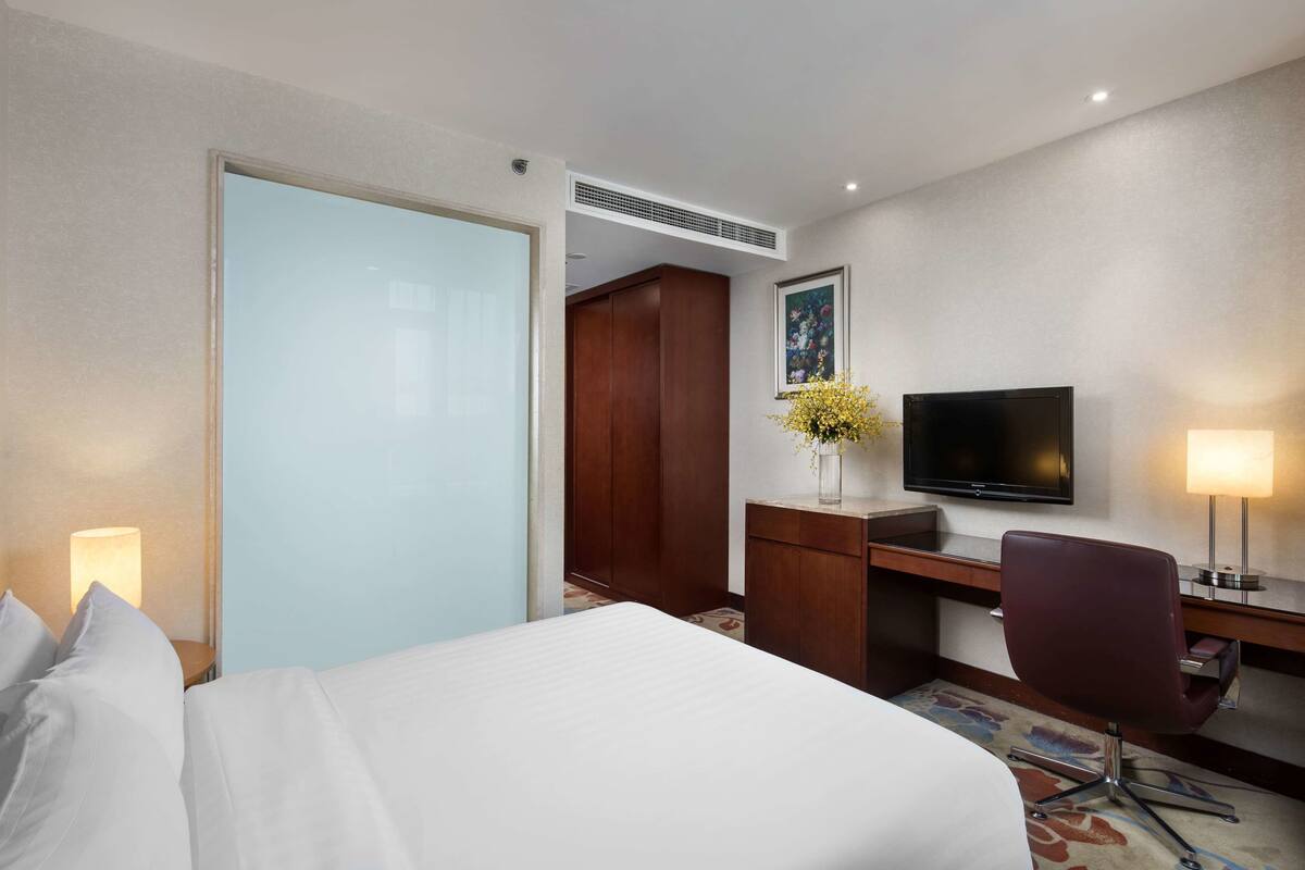 Een hotelkamer met een bed, een bureau met een televisie, een stoel en een bureaulamp.