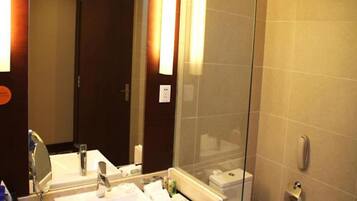 A modern bathroom with a glass shower enclosure, a white sink with a mirror, and a toilet.