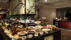 Disposição de buffet com diversos pratos e uma parede decorativa.