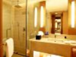A hotel bathroom with a glass shower enclosure, a sink with a mirror, and a toilet.
