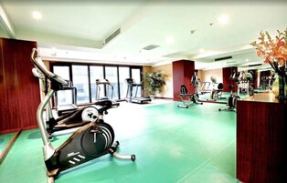 A gym with exercise equipment, large windows, and a green floor.