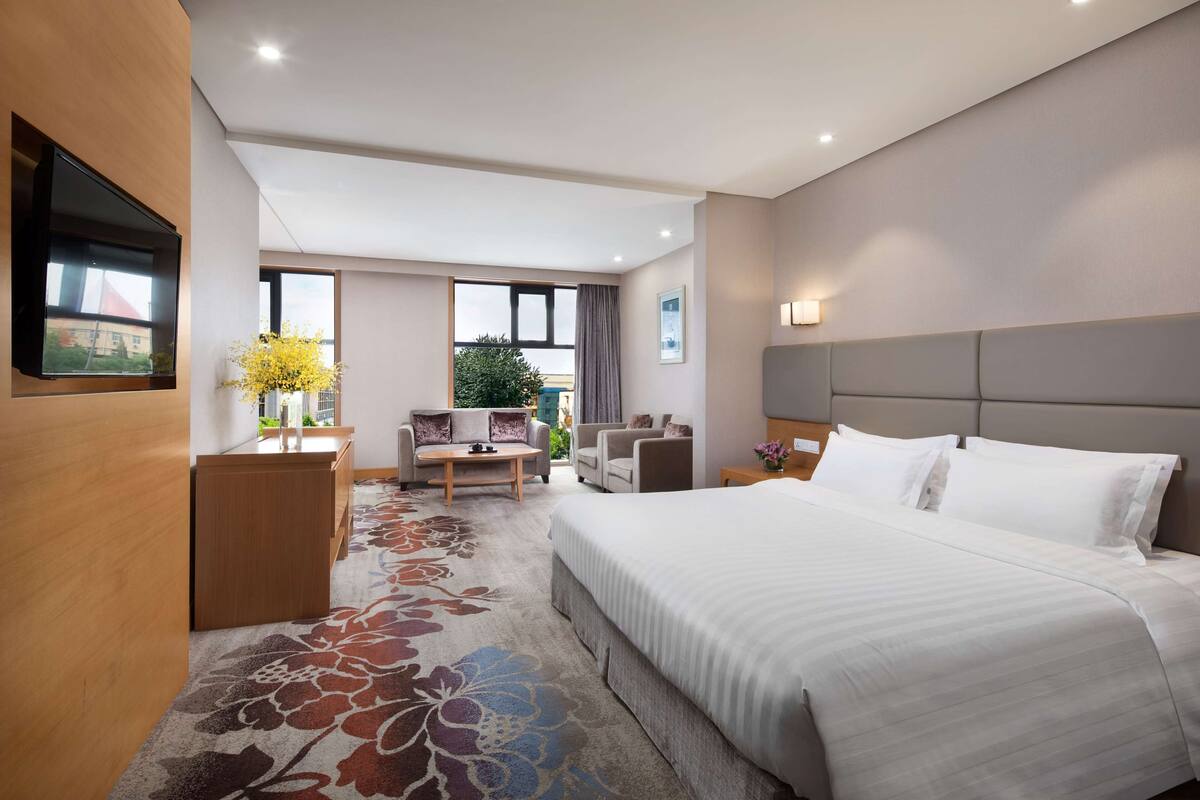 Een hotelkamer met een groot bed, een bureau, een bank en een televisie.