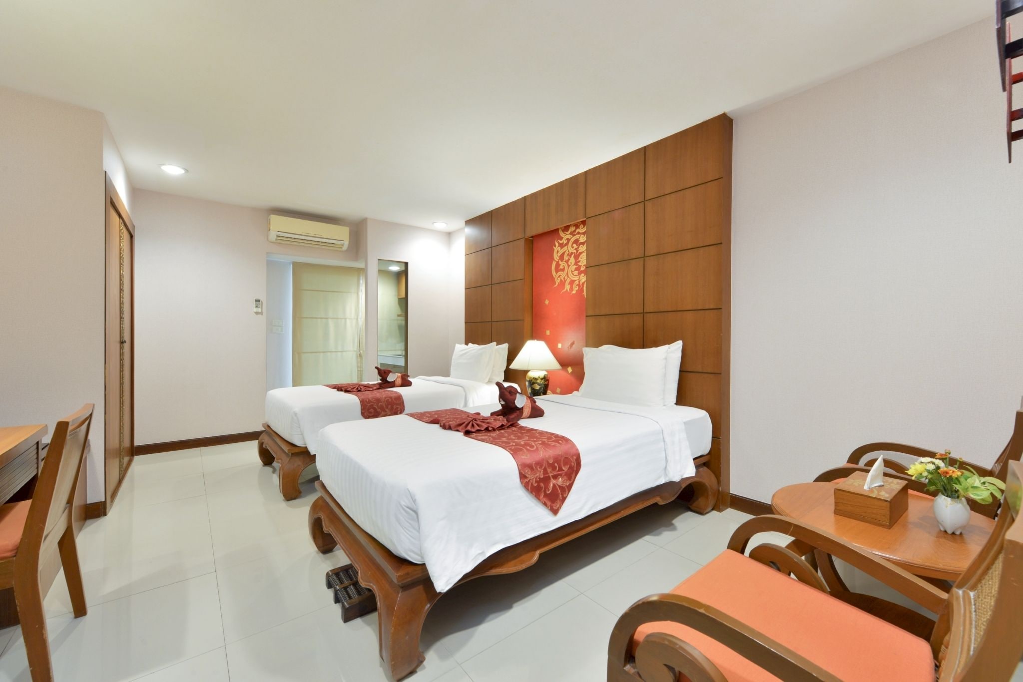A hotel room with two beds, a dining area, and a bathroom.