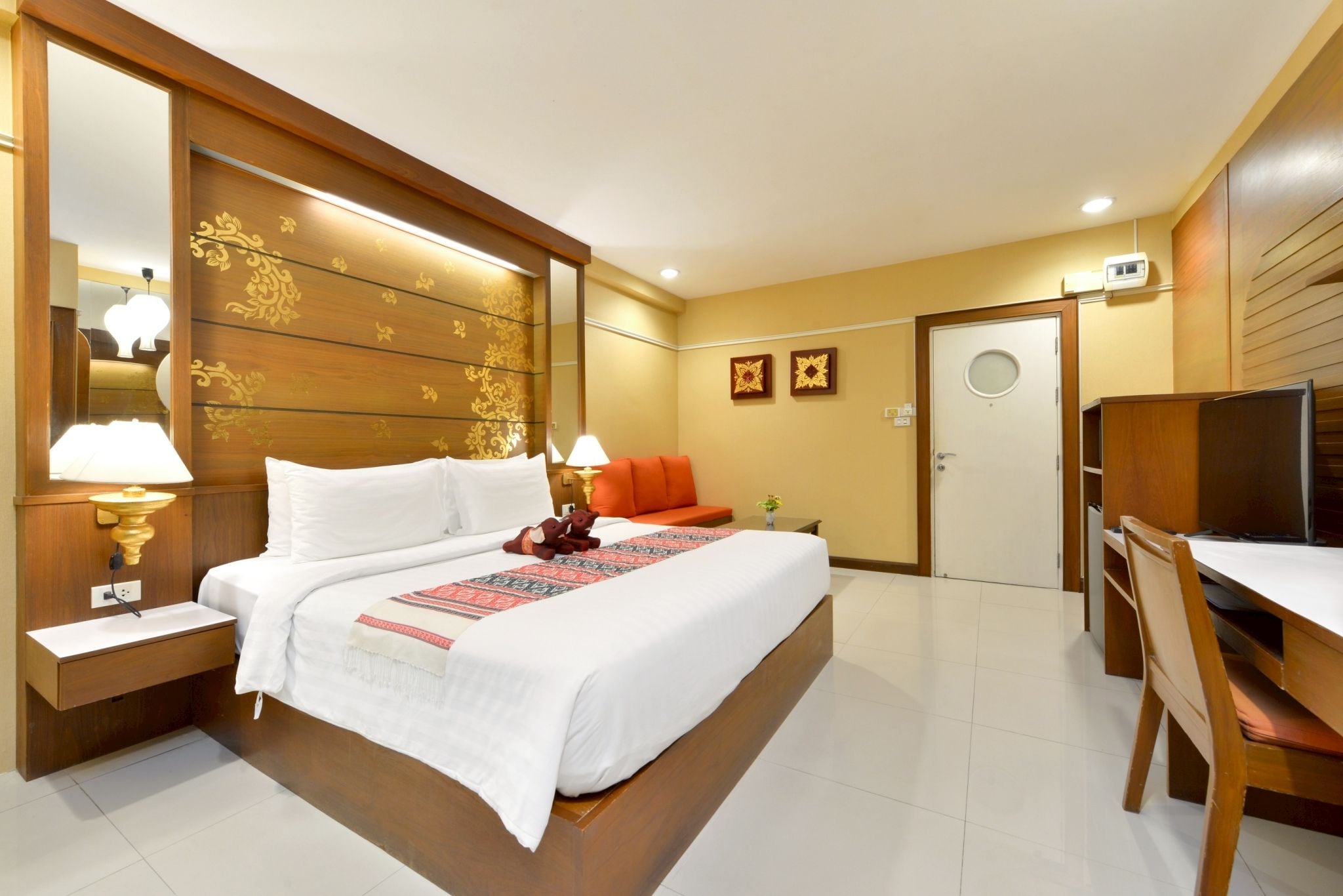 A hotel room with a large bed, bedside lamps, a desk with a chair, and a television.