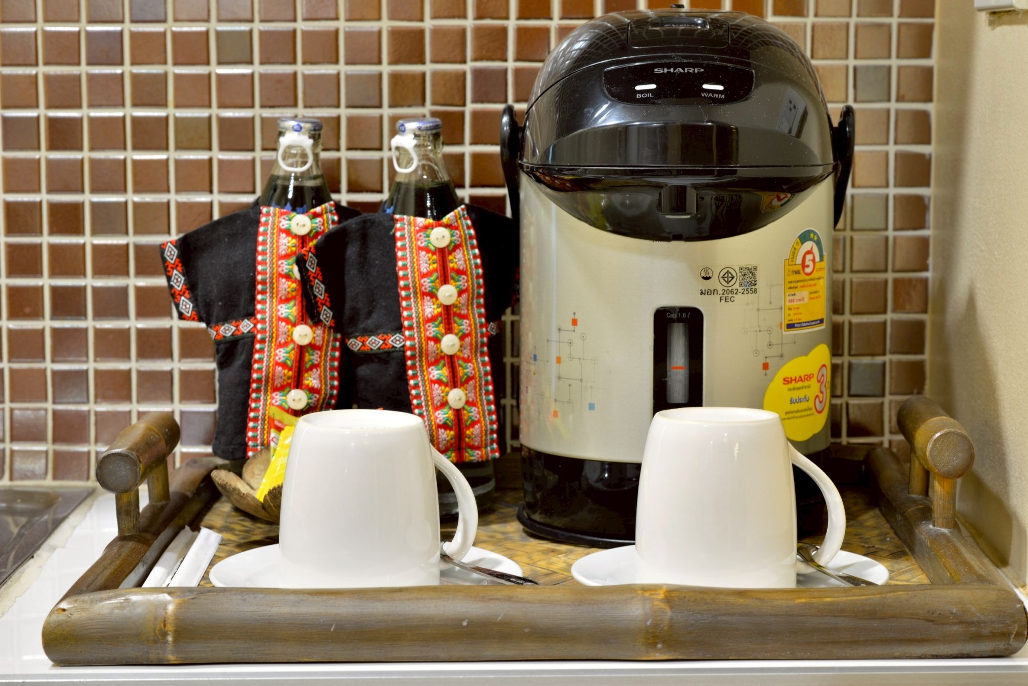 A kitchen area with a coffee maker, two cups, and a tray with wooden utensils.
