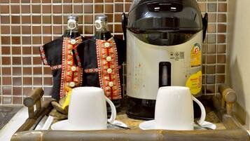 A kitchen area with a coffee maker, two cups, and a tray with wooden utensils.