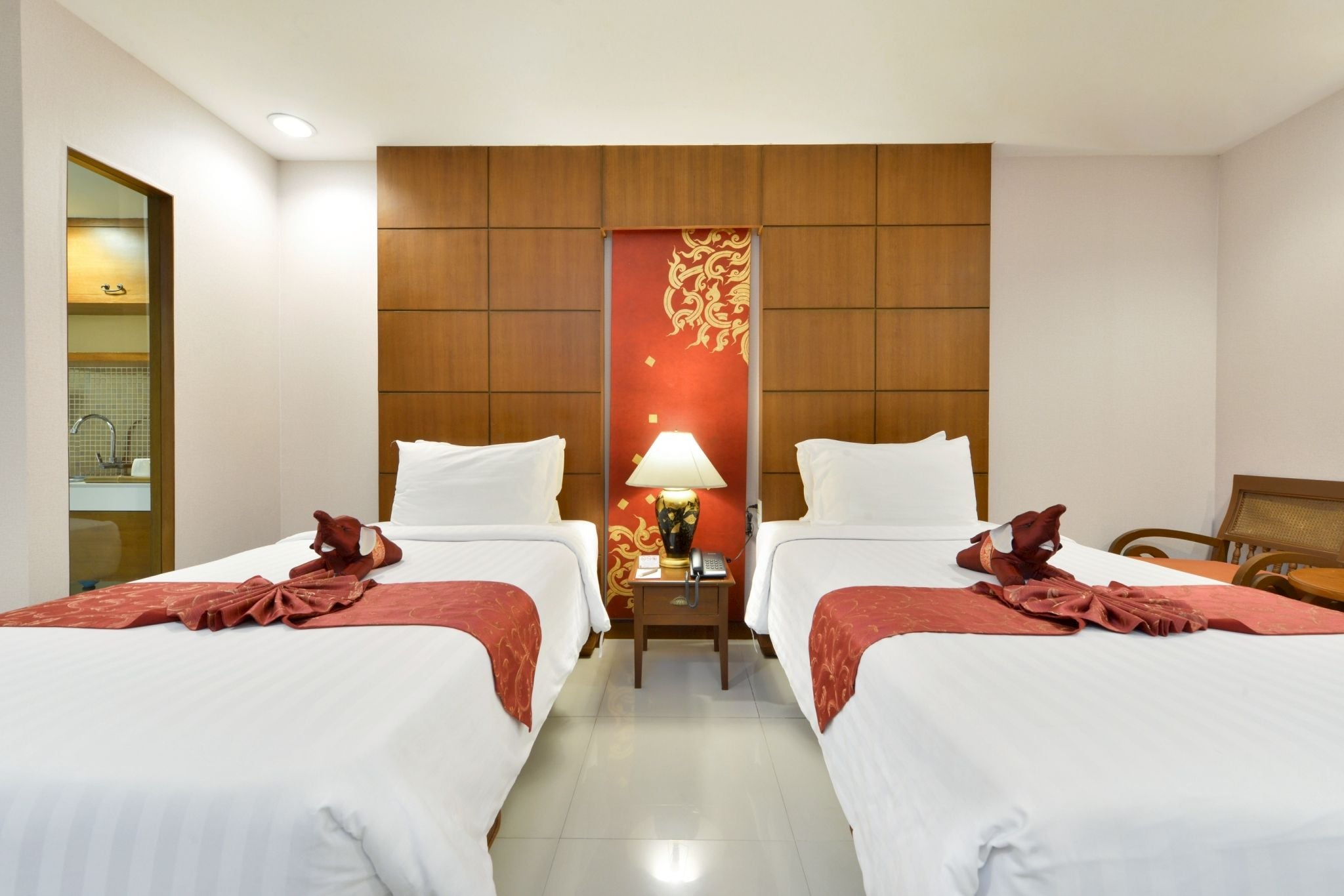 A hotel room with two beds, a nightstand with a lamp, and a decorative wall panel.