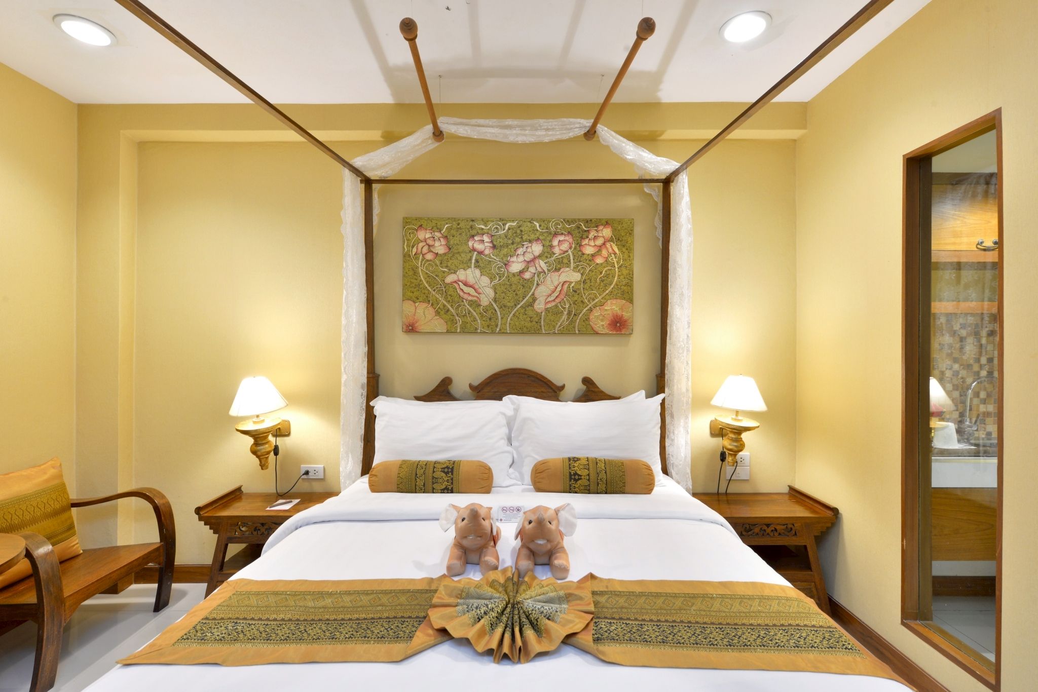 A hotel room with a large bed, two nightstands, a mirror, and a floral artwork on the wall.