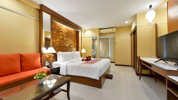 A hotel room with a bed, a sofa, a desk, and a television.