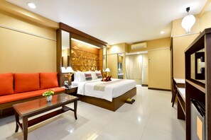 A hotel room with a bed, a sofa, a coffee table, a mirror, and a television. - Mariya Boutique Residence at Suvarnabhumi Airport (Bangkok)