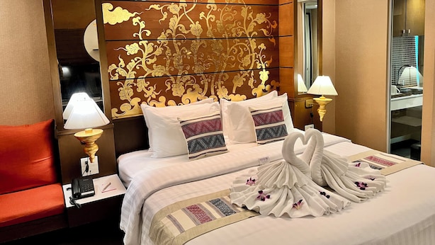A hotel room with a large bed, two bedside lamps, a red chair, and a decorative headboard. - Mariya Boutique Residence at Suvarnabhumi Airport (Bangkok)
