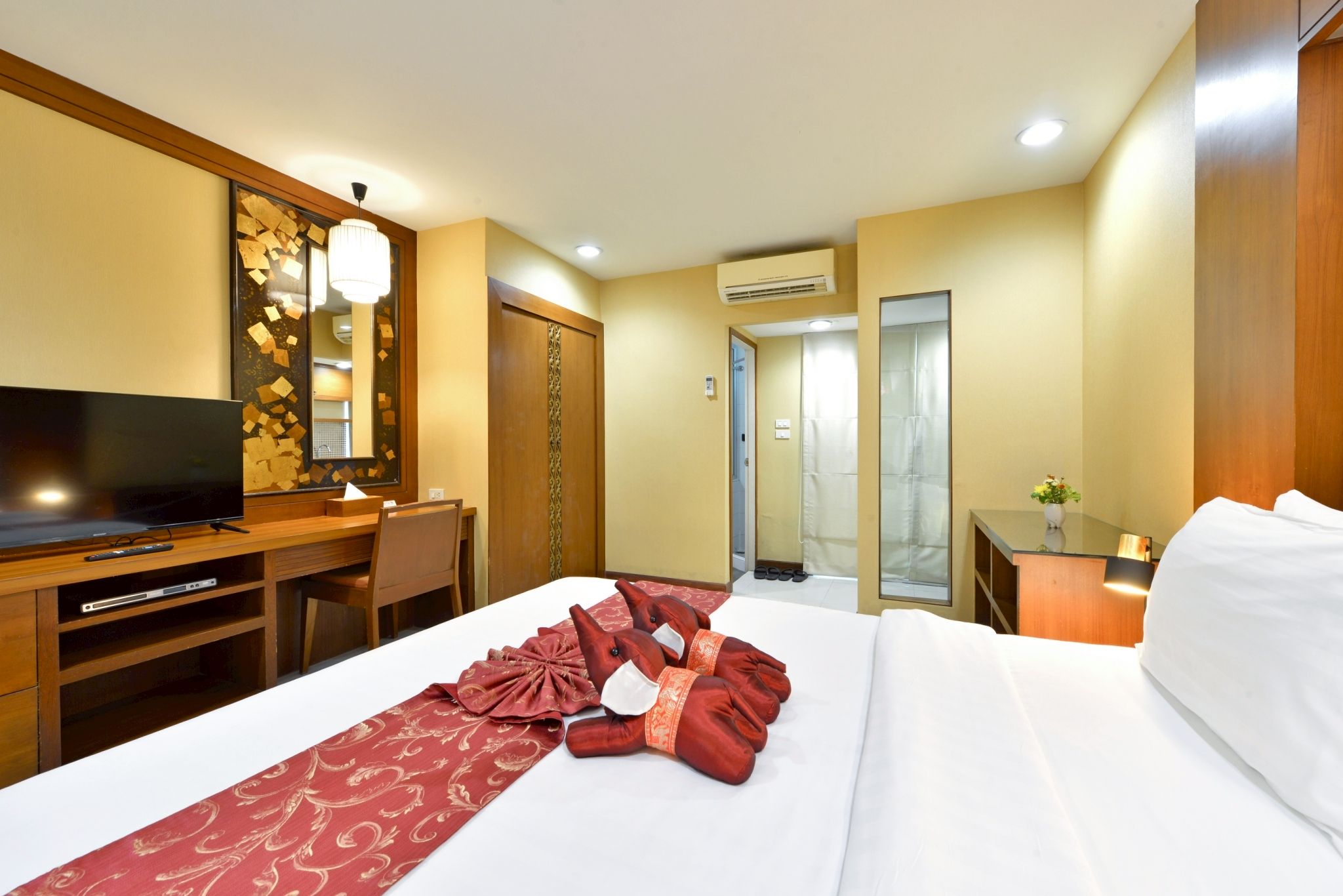 A hotel room with a bed, a desk, a television, and a mirror.