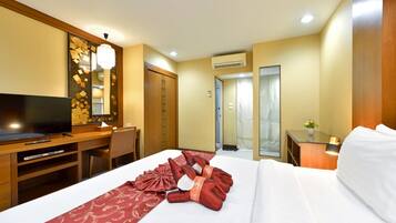 A hotel room with a bed, a desk, a television, and a mirror.
