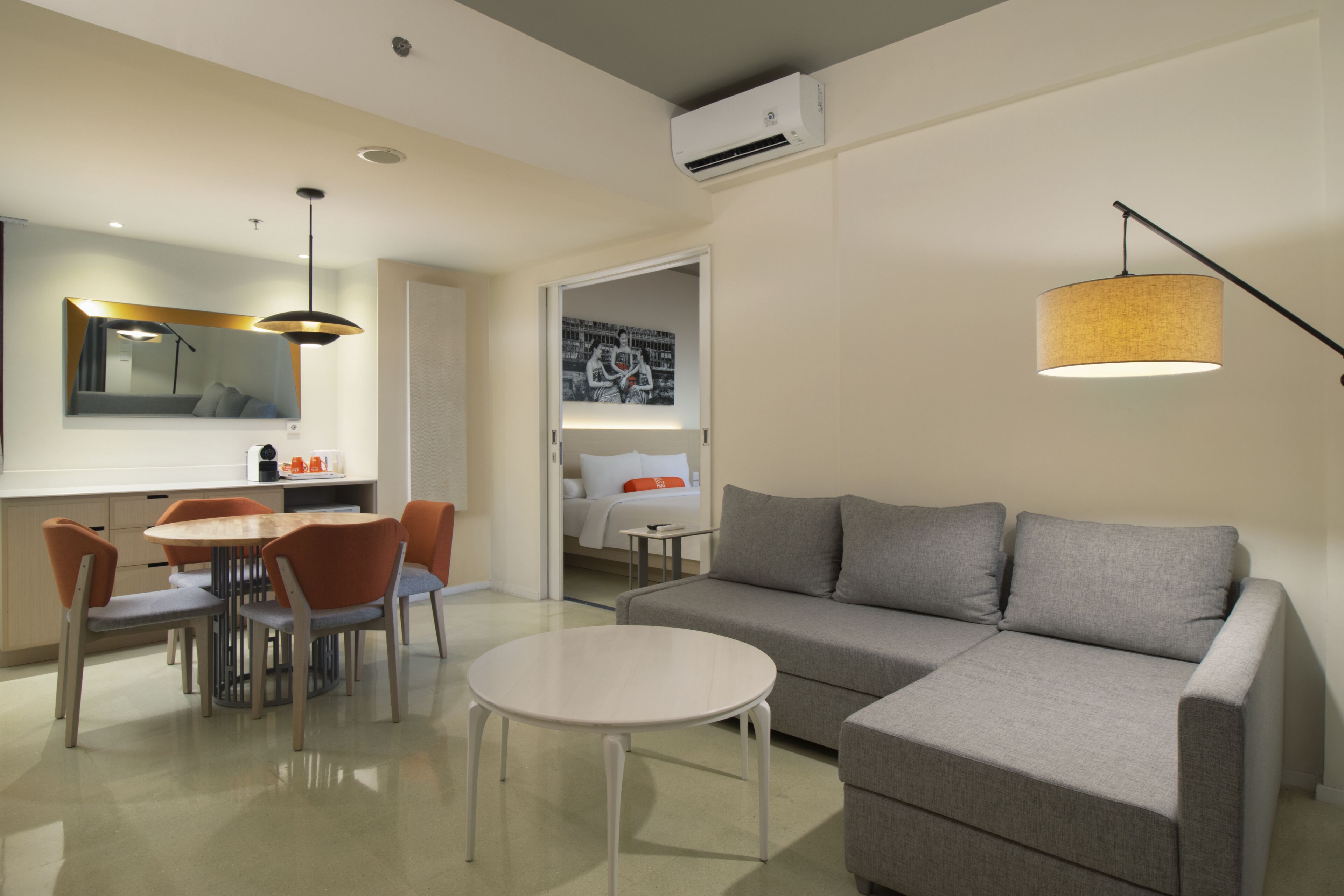 Una sala de estar moderna con un sofá gris, una mesa redonda y un comedor con una mesa y sillas.