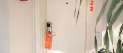 A door with a security lock and a "Do Not Disturb" sign, a plant in the foreground, and a number "122" on the wall.
