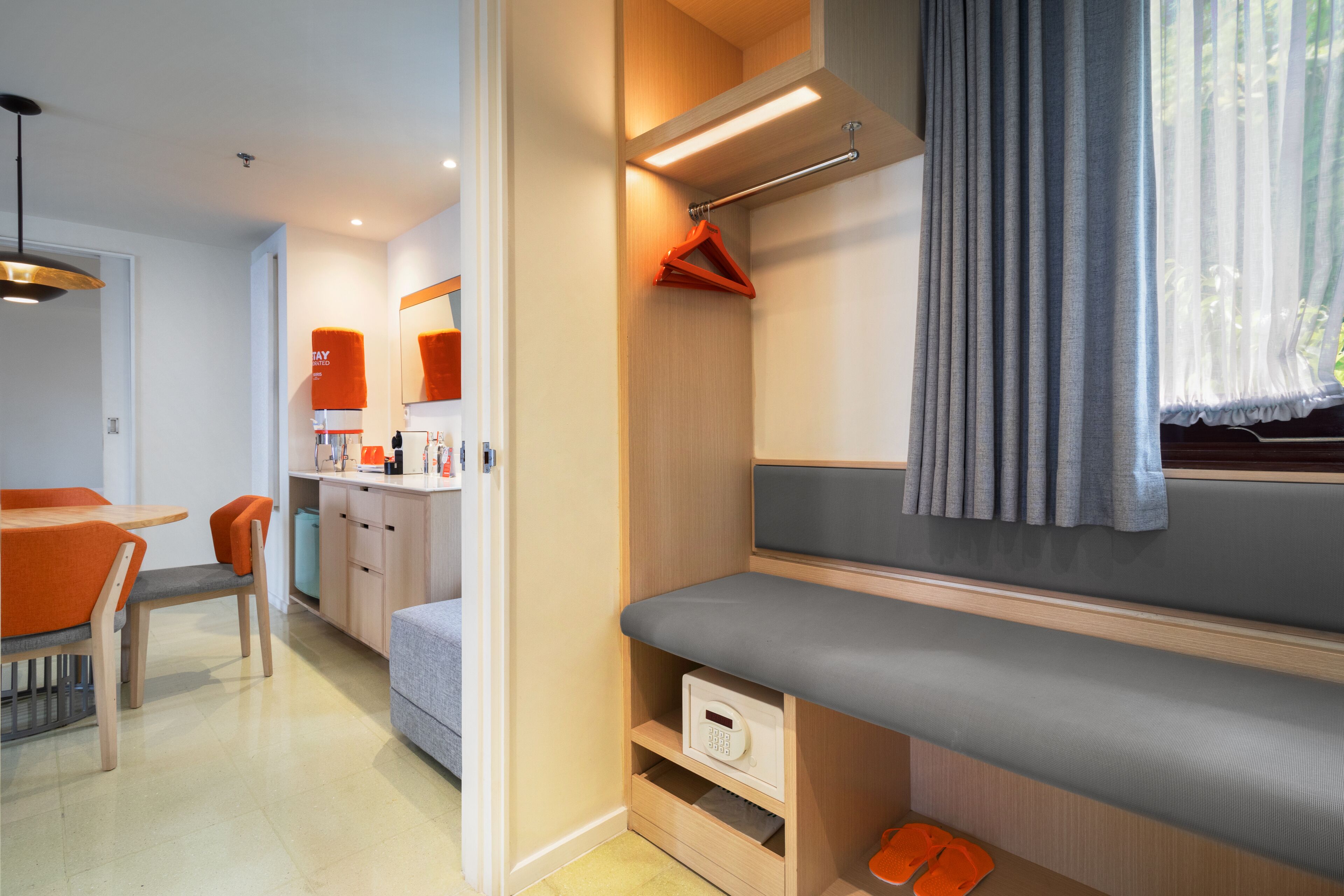 A modern hotel room with a seating area, a small kitchenette, and a bathroom.