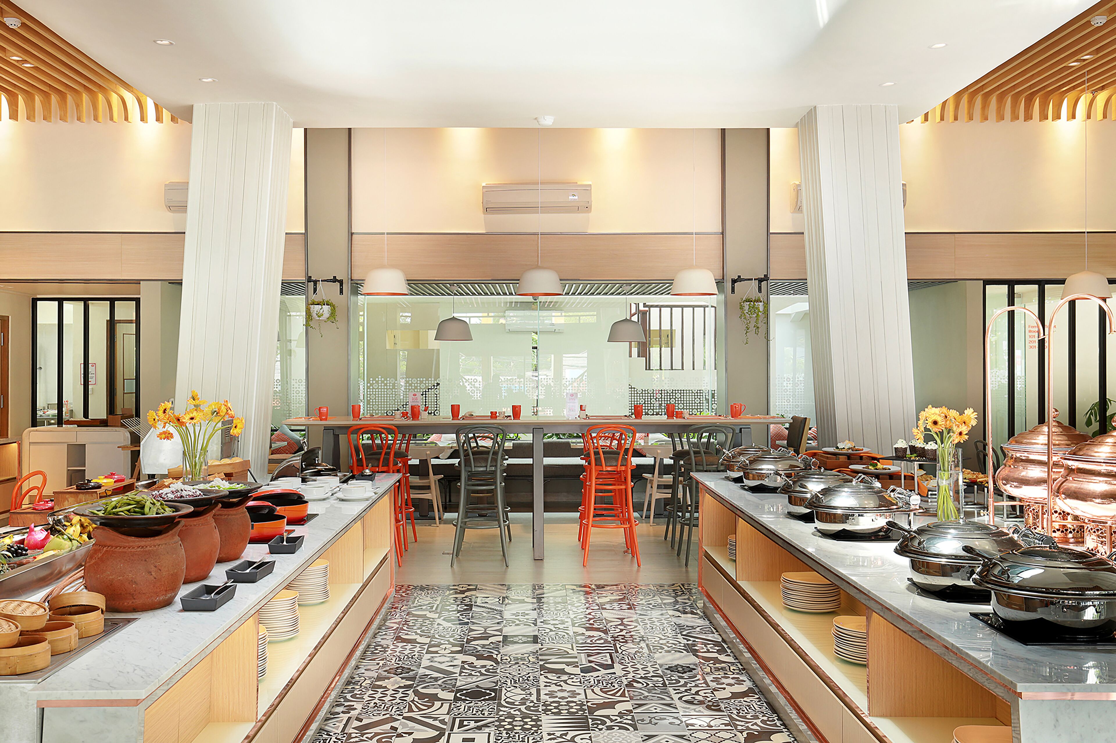 A modern hotel kitchen with a long buffet table, multiple serving stations, and a central island.