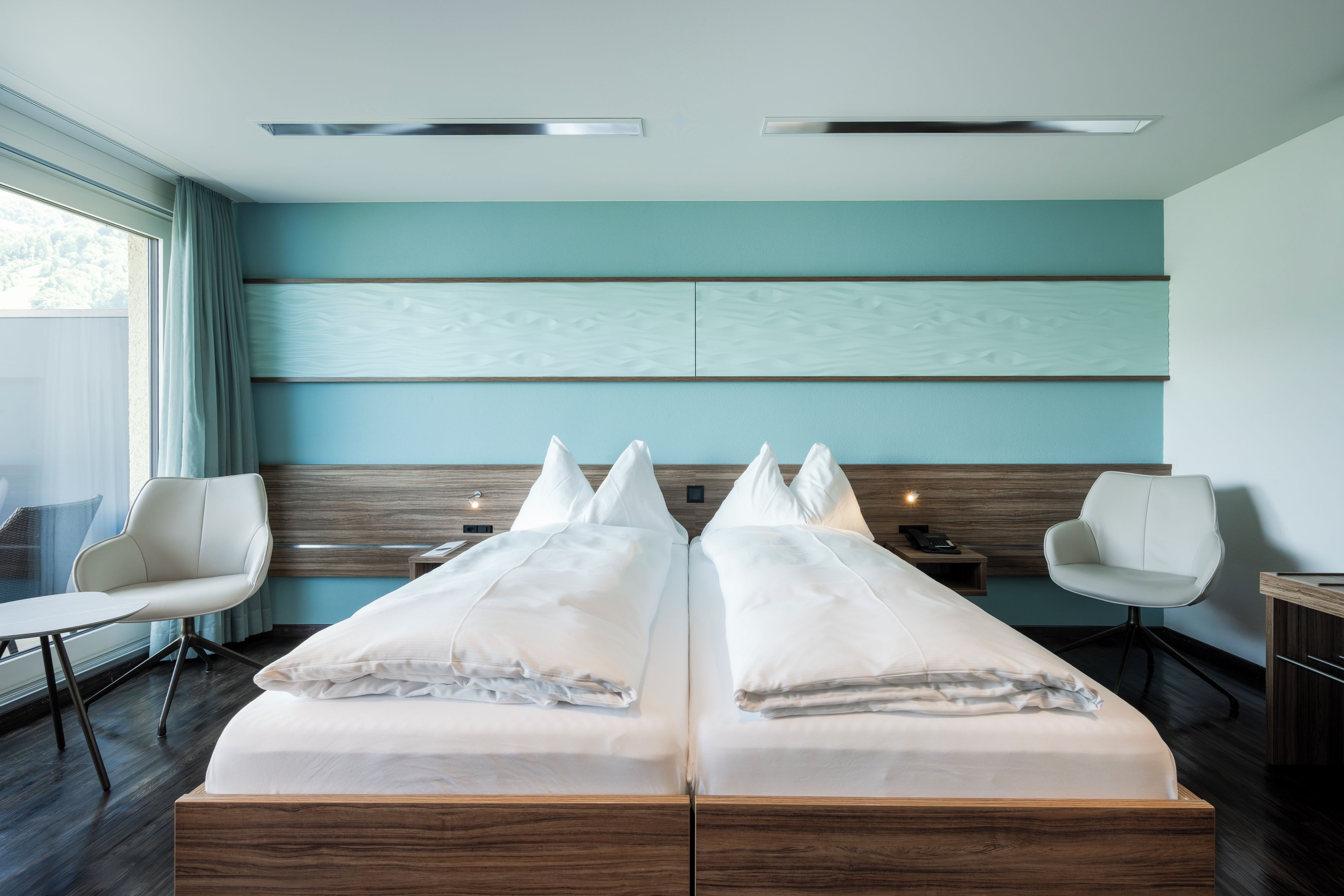 Una habitación de hotel moderna con una cama grande, dos mesitas de noche, un escritorio y una silla.