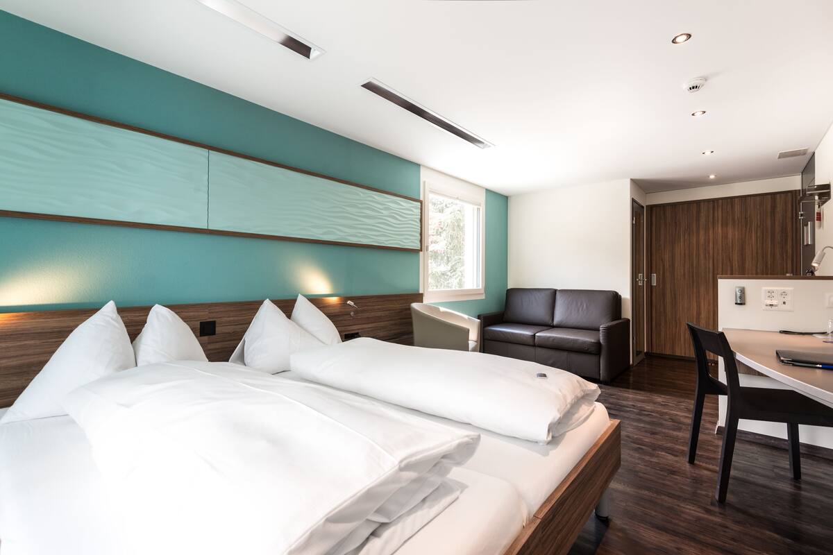 Una habitación de hotel moderna con una cama grande, un escritorio y un sillón de cuero.