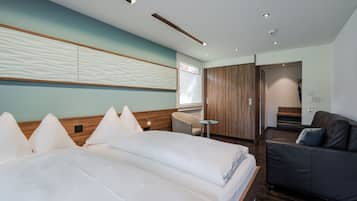 Quarto de hotel moderno com uma cama grande, uma escrivaninha, um sofá e um guarda-roupa.