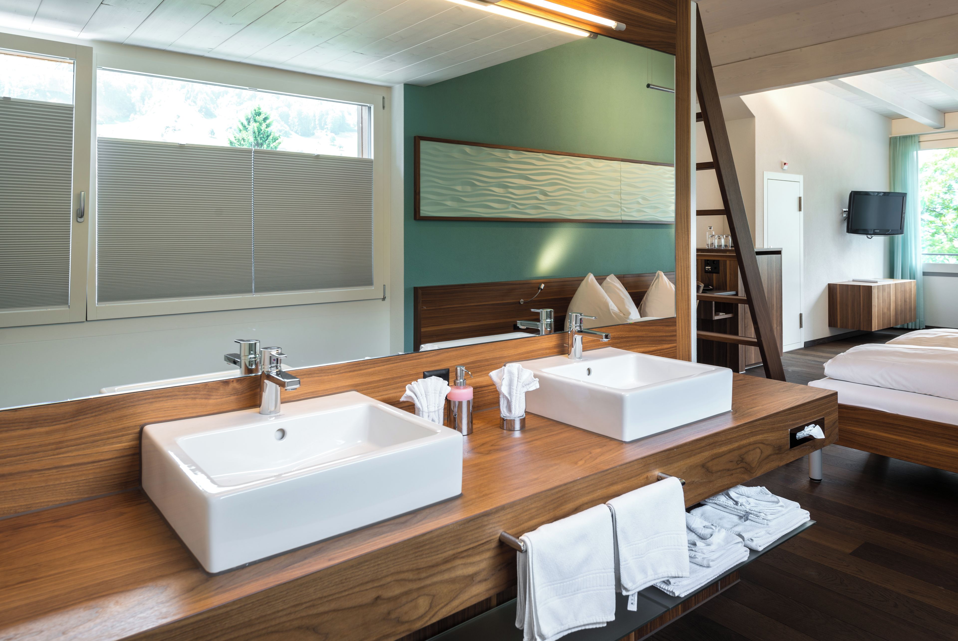 A modern bathroom with two sinks, a large mirror, and a wooden vanity.