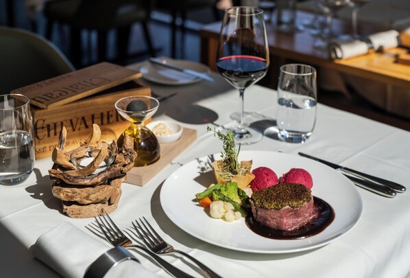 A dining table with a plate of food, wine glasses, and cutlery. - Hotel Nidwaldnerhof direkt am See Swiss Quality (Beckenried)