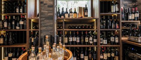 A wine cellar with wooden shelves and a barrel filled with bottles.