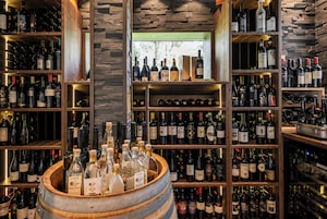 Una bodega con estantes de madera y un barril lleno de botellas.
