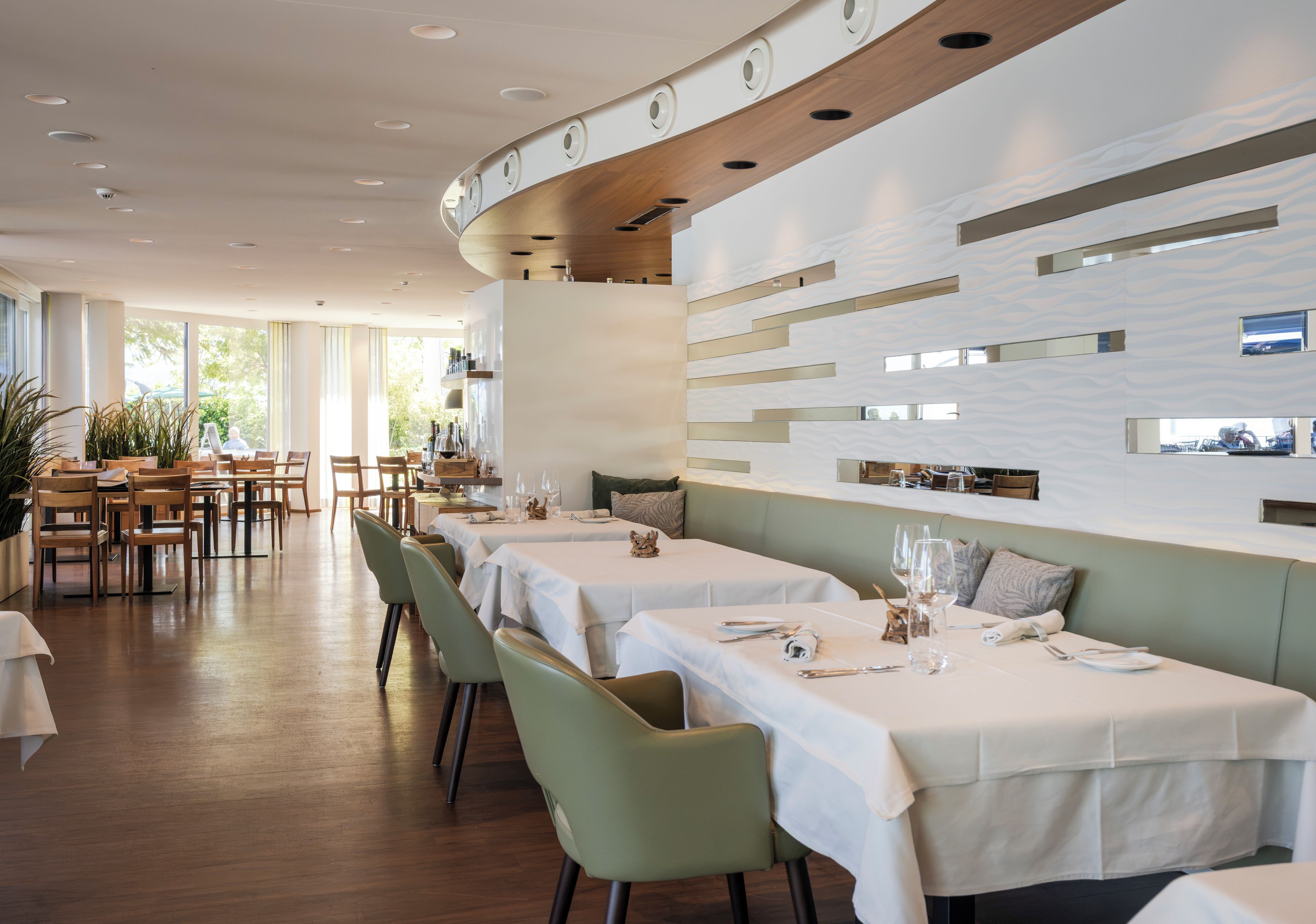 Een restaurant met lange tafels, stoelen en een modern interieur.