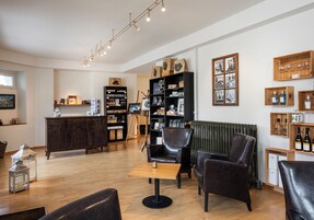 Amplia sala de estar con suelo de madera, asientos de cuero y una mesa central.