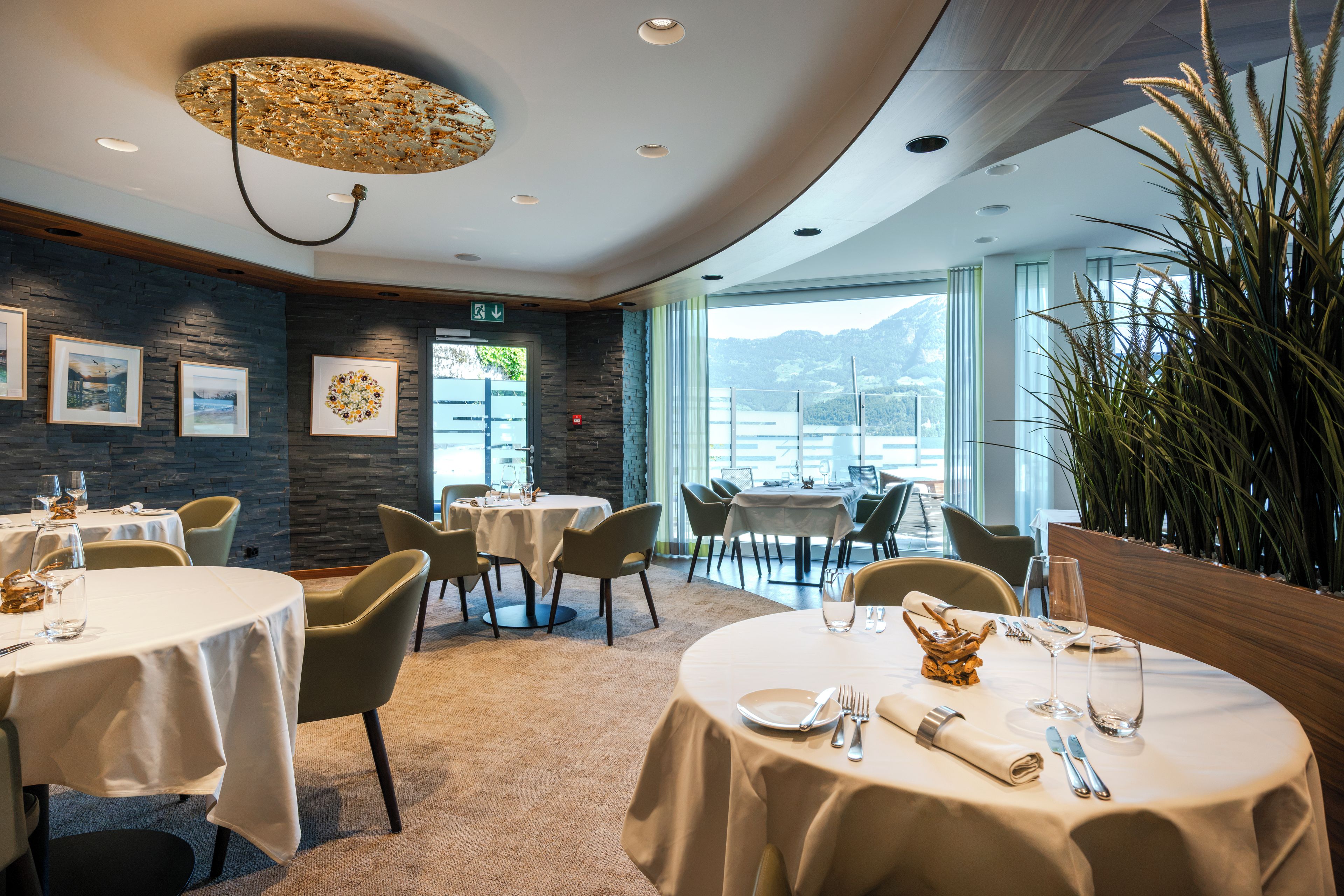 A restaurant with round tables, chairs, and a view of the mountains.