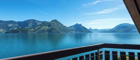 A balcony with a view of a calm lake and mountains.
