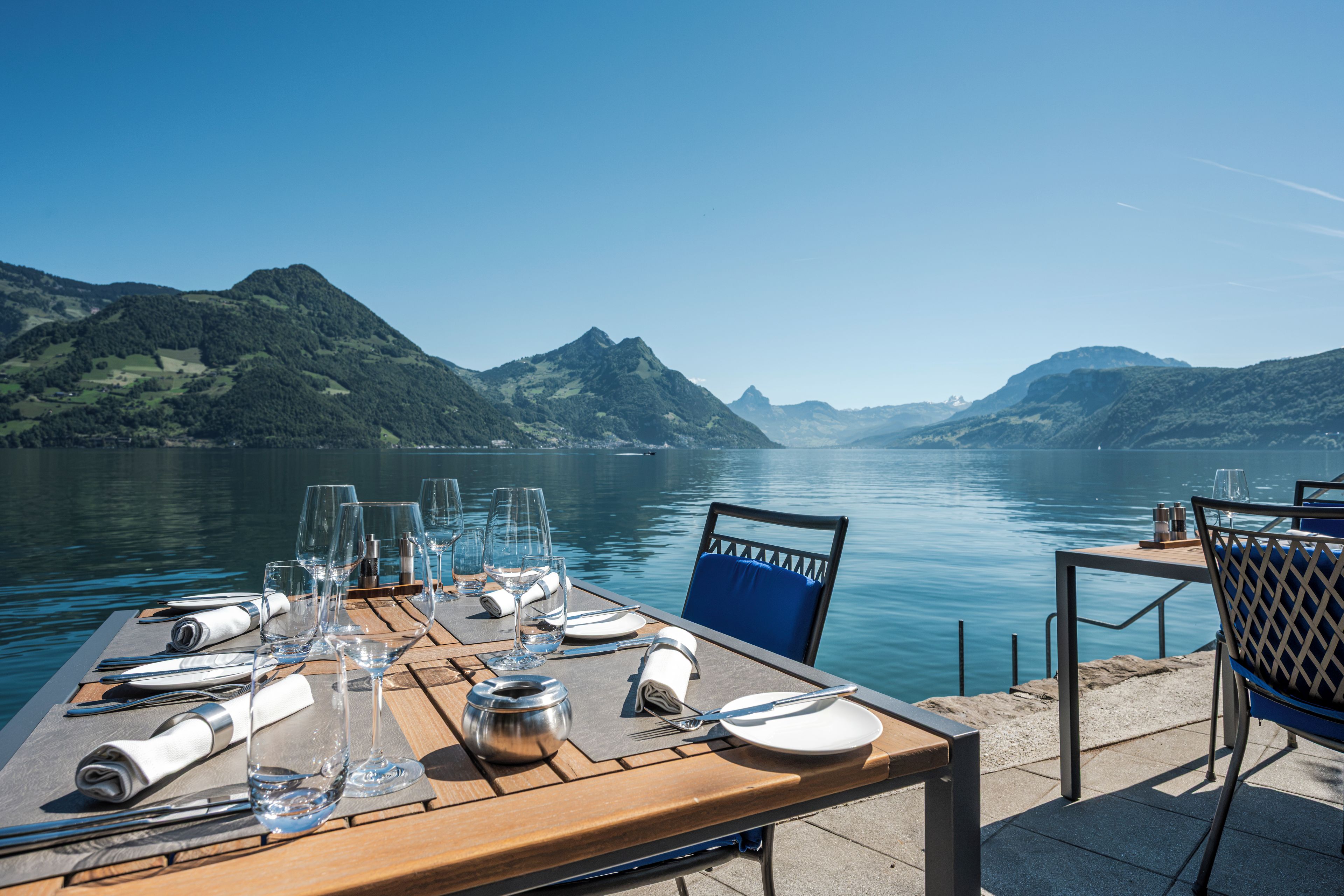 A table set for dining with a view of a lake and mountains.