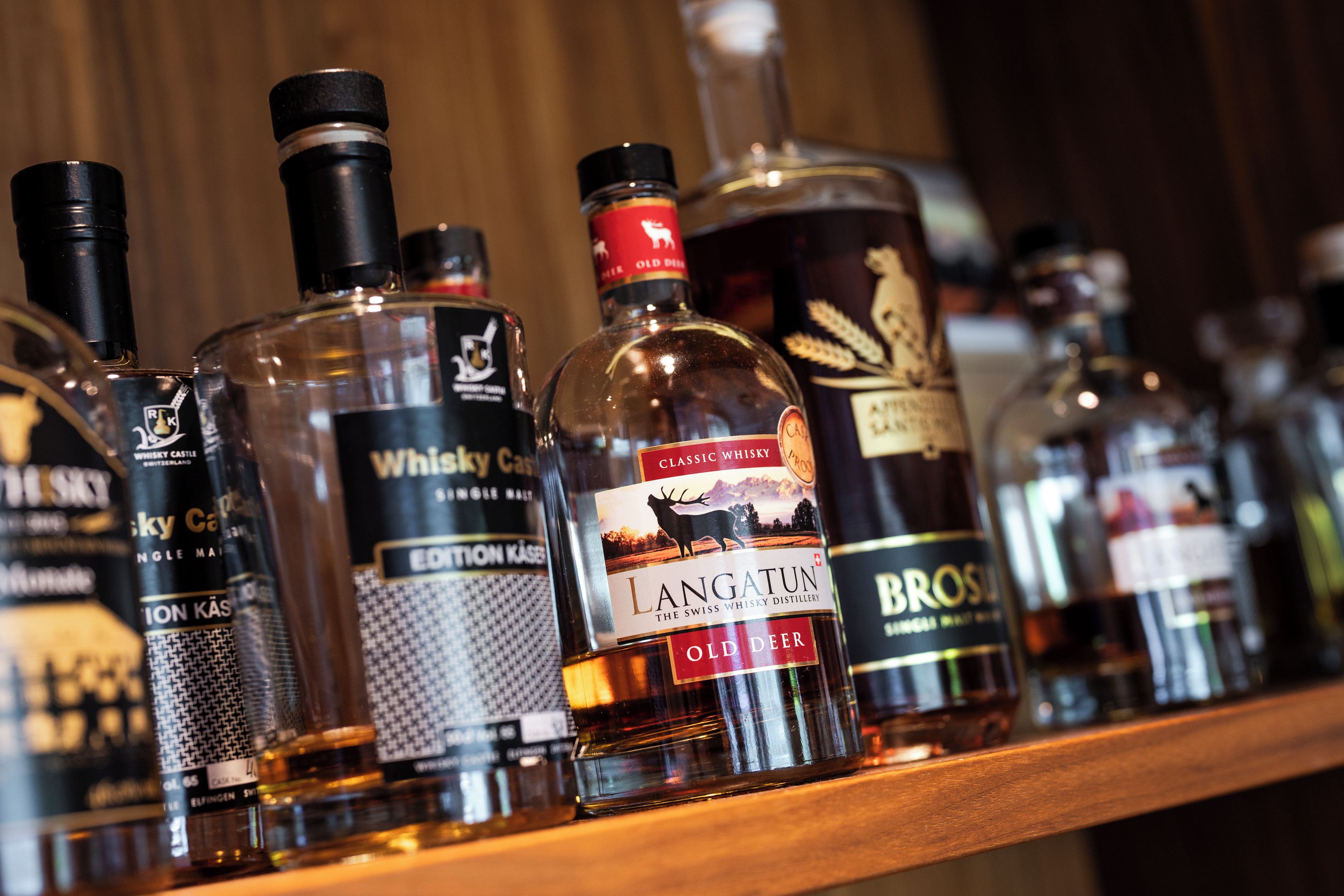 A variety of whisky bottles on a shelf.