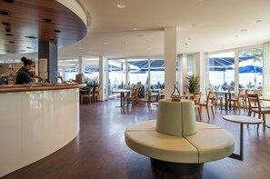 A modern interior with a curved counter, seating area, and large windows. - Hotel Nidwaldnerhof direkt am See Swiss Quality (Beckenried)