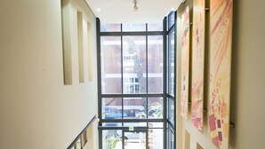 Um corredor com parede de vidro, escada e vista para o exterior.
