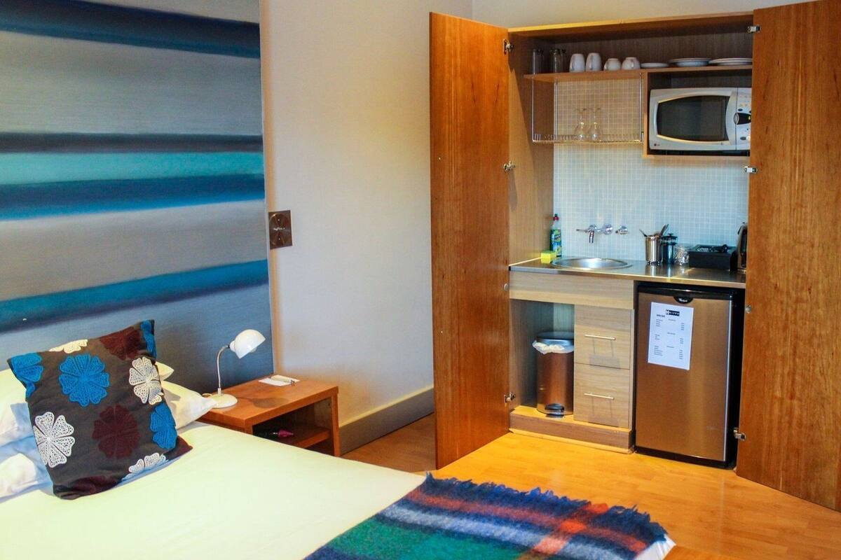 A compact kitchen with a microwave, sink, and a small refrigerator.