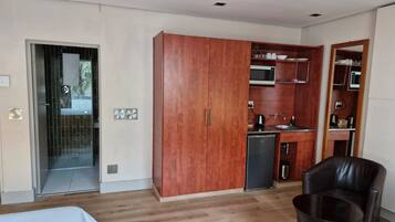 Un espacio habitable pequeño con kitchenette, armario y zona de estar.